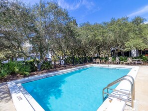 A rectangular swimming pool with a metal ladder, surrounded by trees and a fence. - Inlet Dunes #102 | Steps to Beach + Pool! (30A)
