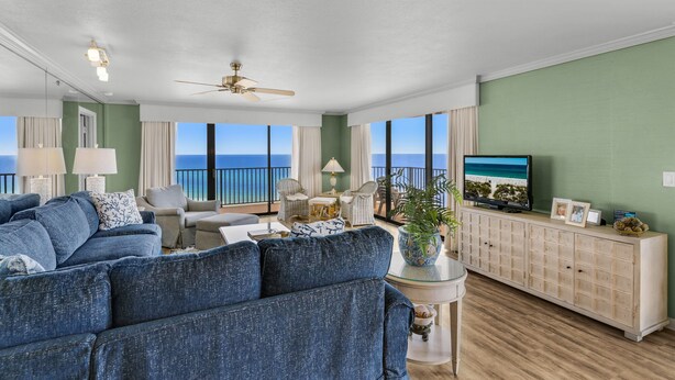 A spacious living room with a large sofa, a television, and a view of the ocean.