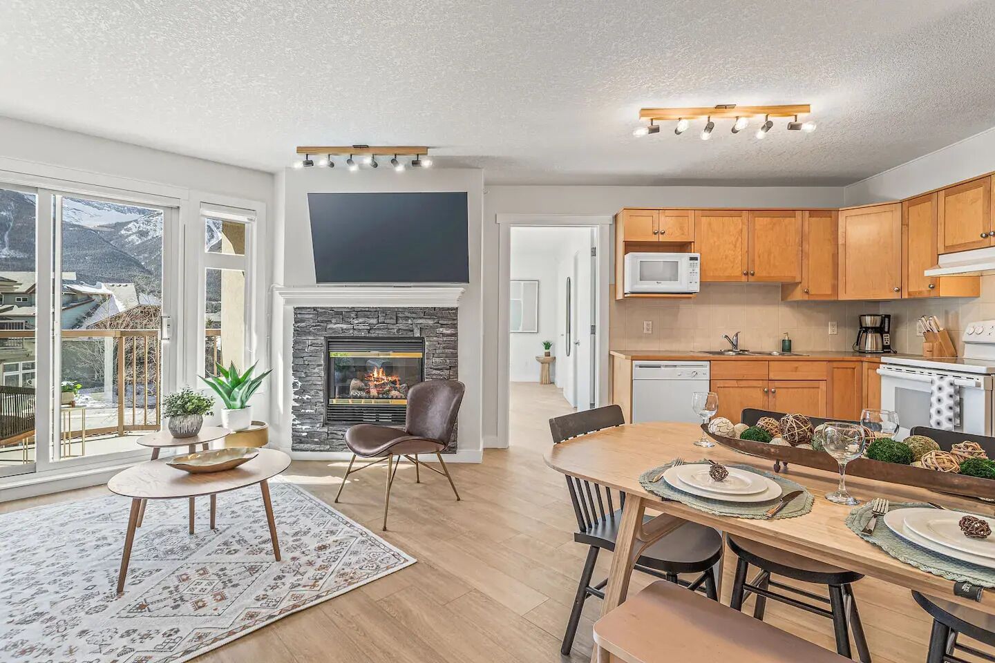 A modern kitchen with wooden cabinets, a microwave, and a dining area with a table set for two.