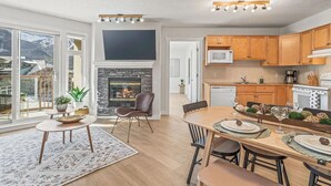 A modern kitchen with wooden cabinets, a microwave, and a dining area with a table set for two.