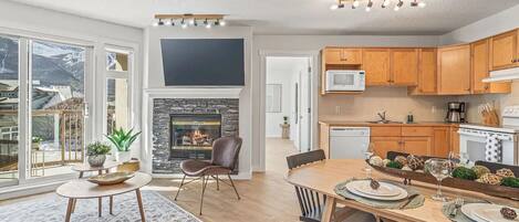 A modern kitchen with wooden cabinets, a microwave, and a dining area with a table set for two.