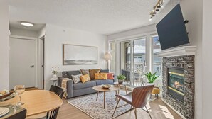 A modern living room with a fireplace, a dining area, and a sofa with cushions.
