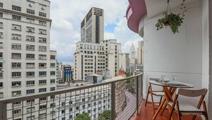 Ein Balkon mit Tisch und Stühlen, mit Blick auf eine Stadtlandschaft und verschiedene Gebäude.
