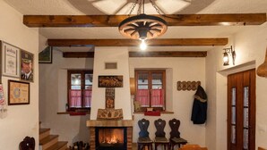 A cozy room with a fireplace, wooden beams, and a dining area with a table set for two. - San Vinogradara - One Bedroom Holiday Home With Hot Tube (Donja Stubica)