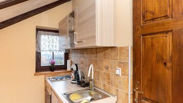 A compact kitchen with wooden cabinets, a sink, and a window with a view.