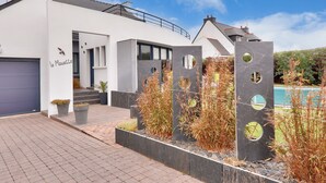 Une maison moderne avec une façade blanche, un garage et une piscine.