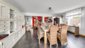 Un coin repas avec des chaises en osier, une table en bois et un lustre moderne.