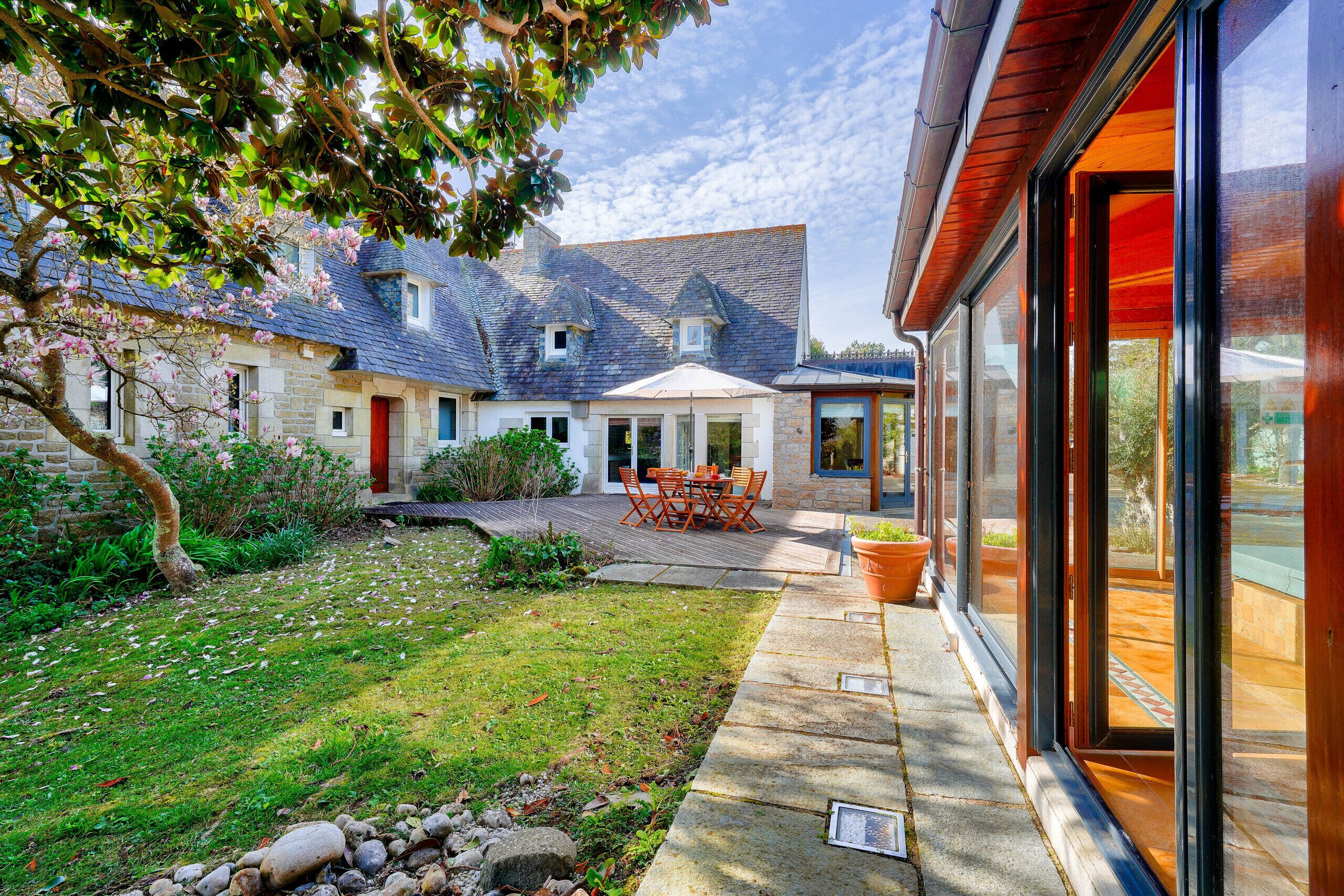 A house with a stone facade, a wooden deck, and a glass door leading to a patio.
