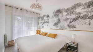 A bedroom with a large bed, a nightstand with a lamp, a wall mural, and sheer curtains. - Flat for 5 at 600m from the beach (La Baule-Escoublac)