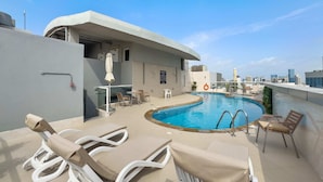 A rooftop pool area with lounge chairs, a small table, and a glass-enclosed seating area. - Silkhaus Uniestate Sports Tower - DSC (Dubai)