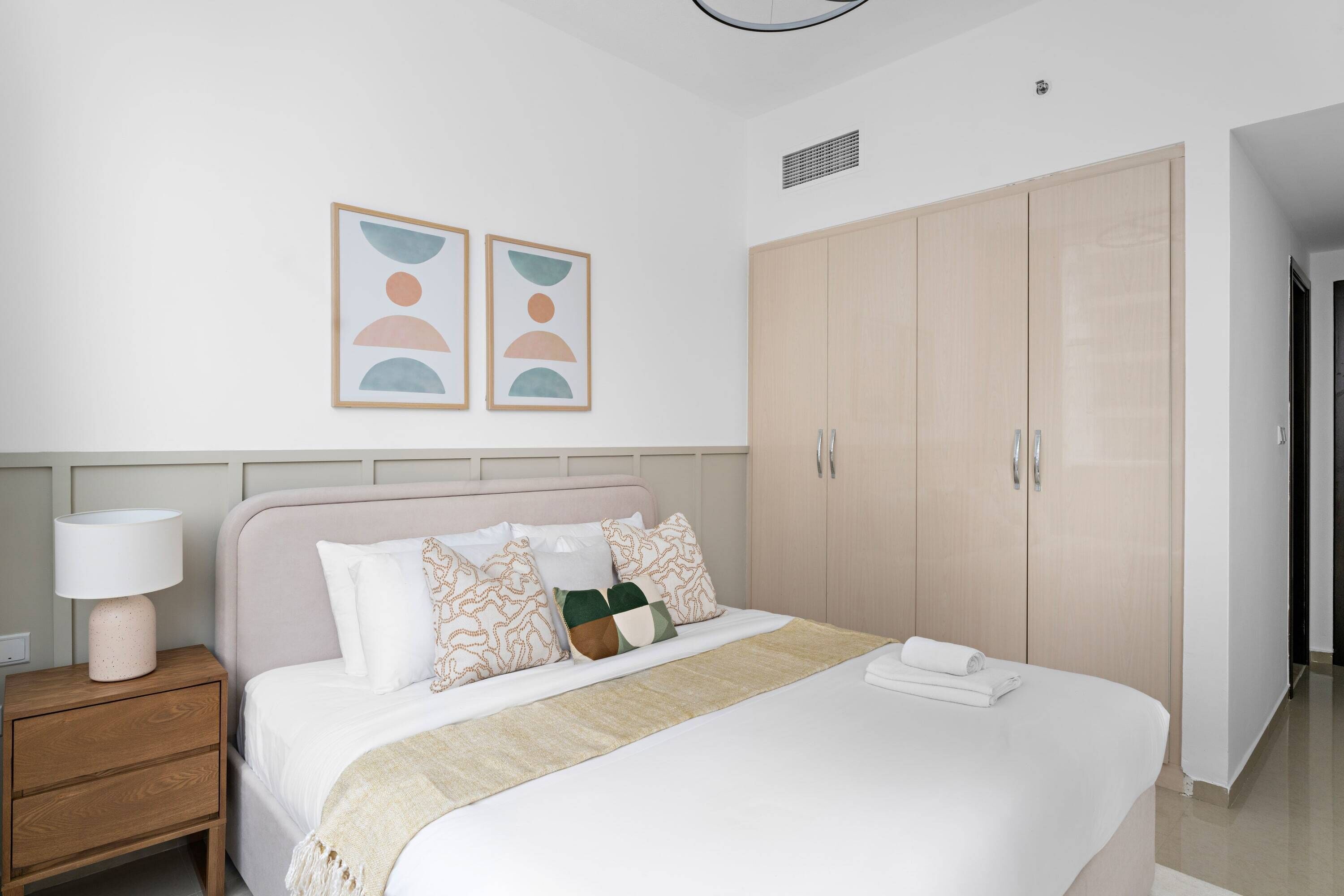 Une chambre à coucher comprenant un lit, une table de chevet, une armoire et des œuvres d’art murales.