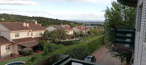 A residential area with houses, a swimming pool, and a view of a distant landscape.
