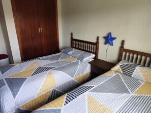 Un dormitorio con dos camas, un armario de madera y una decoración de estrella azul en la pared.