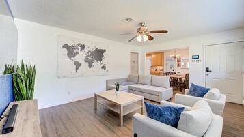 A modern living room with a sofa, armchairs, a coffee table, and a world map on the wall.
