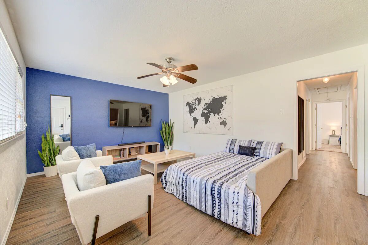 Une chambre moderne avec un lit, un canapé, un bureau et un ventilateur de plafond.