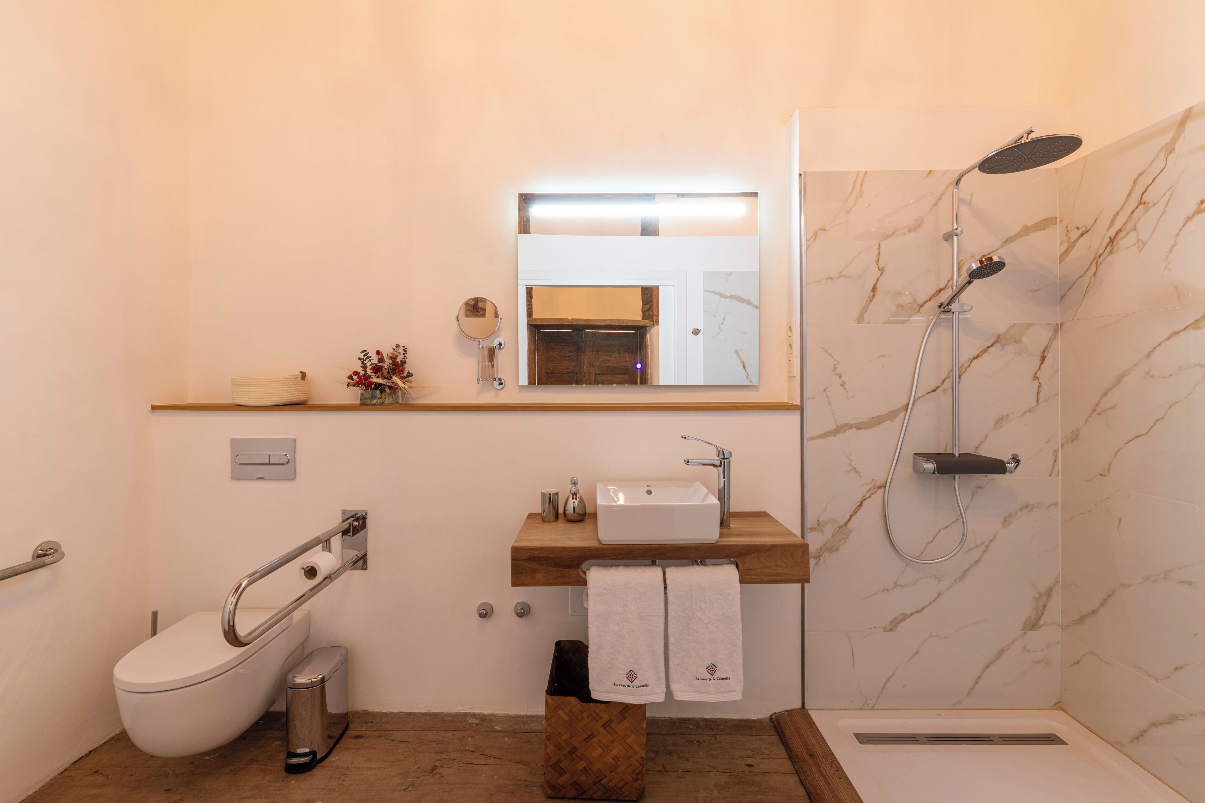 Un baño moderno con inodoro, lavabo, espejo y ducha.