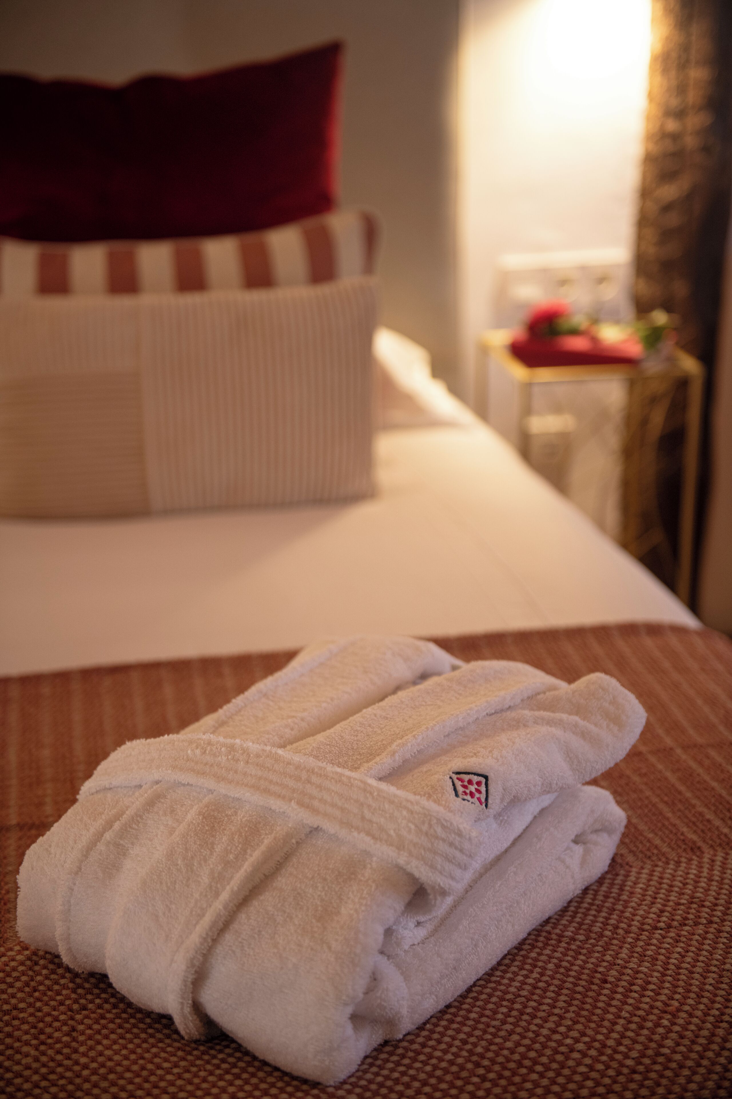 A neatly made bed with white linens and a folded towel on the bed.