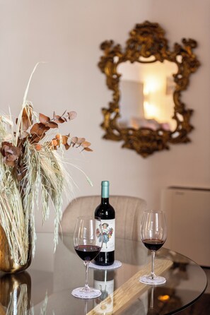 A table with a bottle of wine and two glasses, a vase with dried plants, and a mirror on the wall. - Hotel Emblemático La Casa De La Camelia (San Cristóbal de La Laguna)