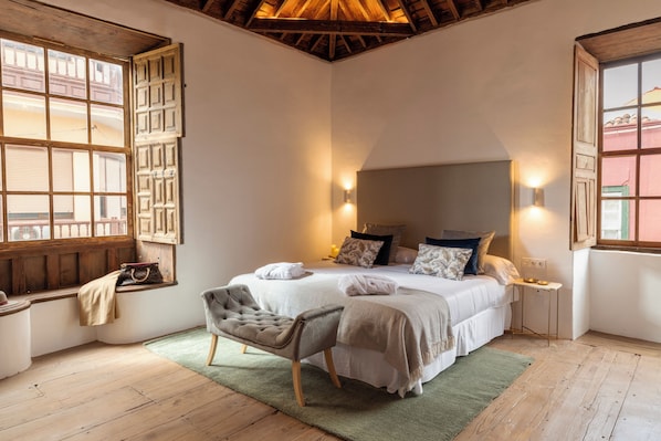 Una camera da letto con un letto grande, una panca, una finestra vista e un soffitto in legno.