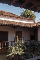 Un edificio tradicional con tejado de tejas, puertas de madera y un balcón con barandilla.