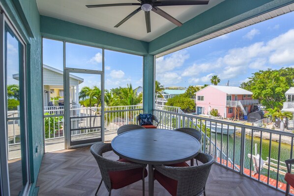 Relax in this serene outdoor space with a round table and four comfortable chairs, surrounded by a glass wall offering a view of the neighborhood.