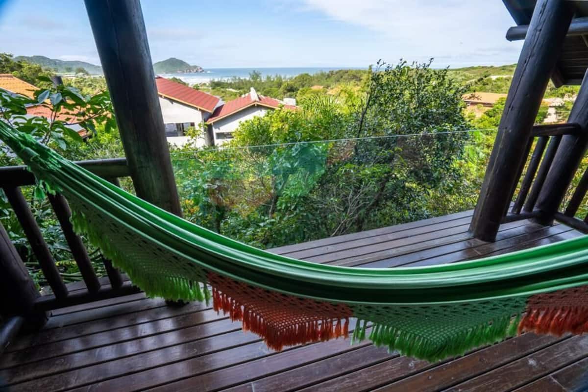 A hammock on a wooden deck overlooking a residential area with houses and greenery.