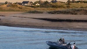 A boat on calm water with a shoreline in the background.