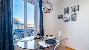 A modern dining area with a glass table and chairs, a decorative mirror, and framed pictures on the wall.