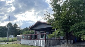 A building with a covered porch, a fenced area, and a grassy yard. - Wild Orchards in the Camas Hills (Camas)