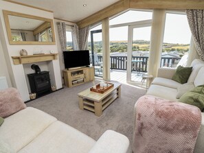 A living room with a fireplace, television, and a balcony with outdoor furniture.