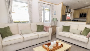 Una sala acogedora con dos sofás, una mesa de centro y una zona de cocina con microondas.