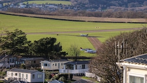 Un paisaje rural con un aeropuerto pequeño, casas y un campo verde.