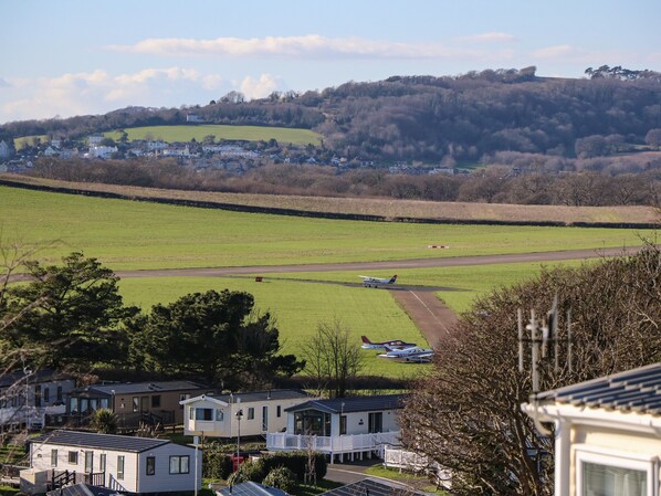 Ländliche Landschaft mit einem kleinen Flughafen, Häusern und einem grünen Feld.