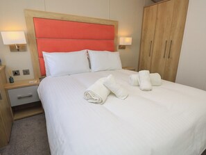 Een hotelkamer met een bed, twee nachtkastjes, een kledingkast van hout en twee wandlampen.