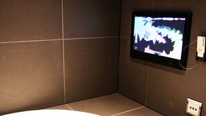 A modern bathroom with a large bathtub, a wall-mounted TV, and a power outlet. - HOTEL Let's (Saitama)