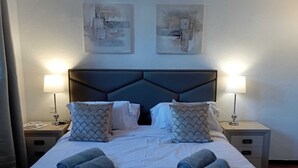 A neatly made bed with two pillows, two rolled towels, and two wall-mounted lamps. - Village house in Benahavis - right in the centre of the village (Benahavís)