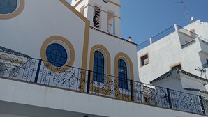 A white building with a bell tower, arched windows, and a balcony with decorative railing. - Village house in Benahavis - right in the centre of the village (Benahavís)