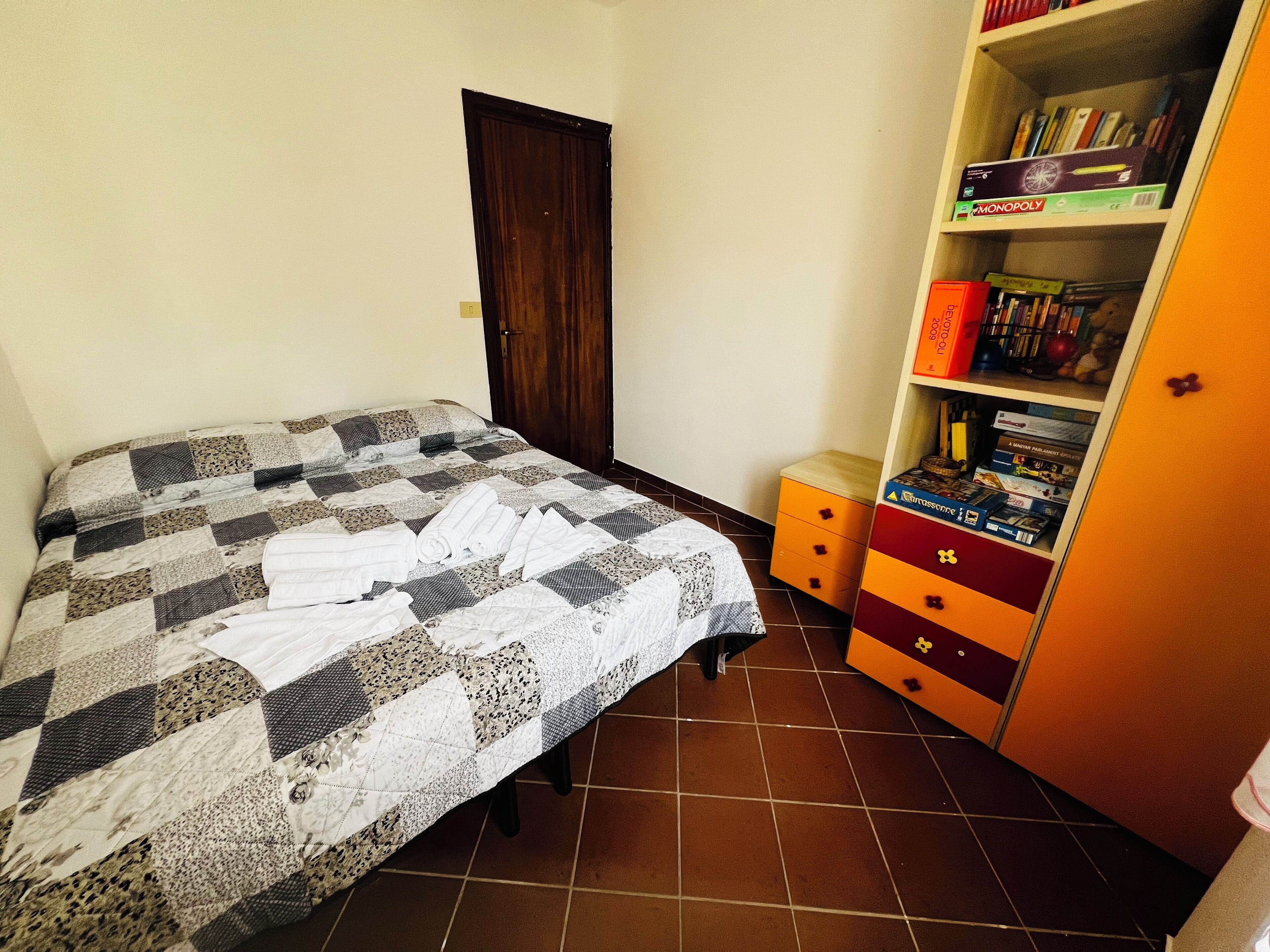 Een slaapkamer met een bed, een kast en een klein tafeltje.