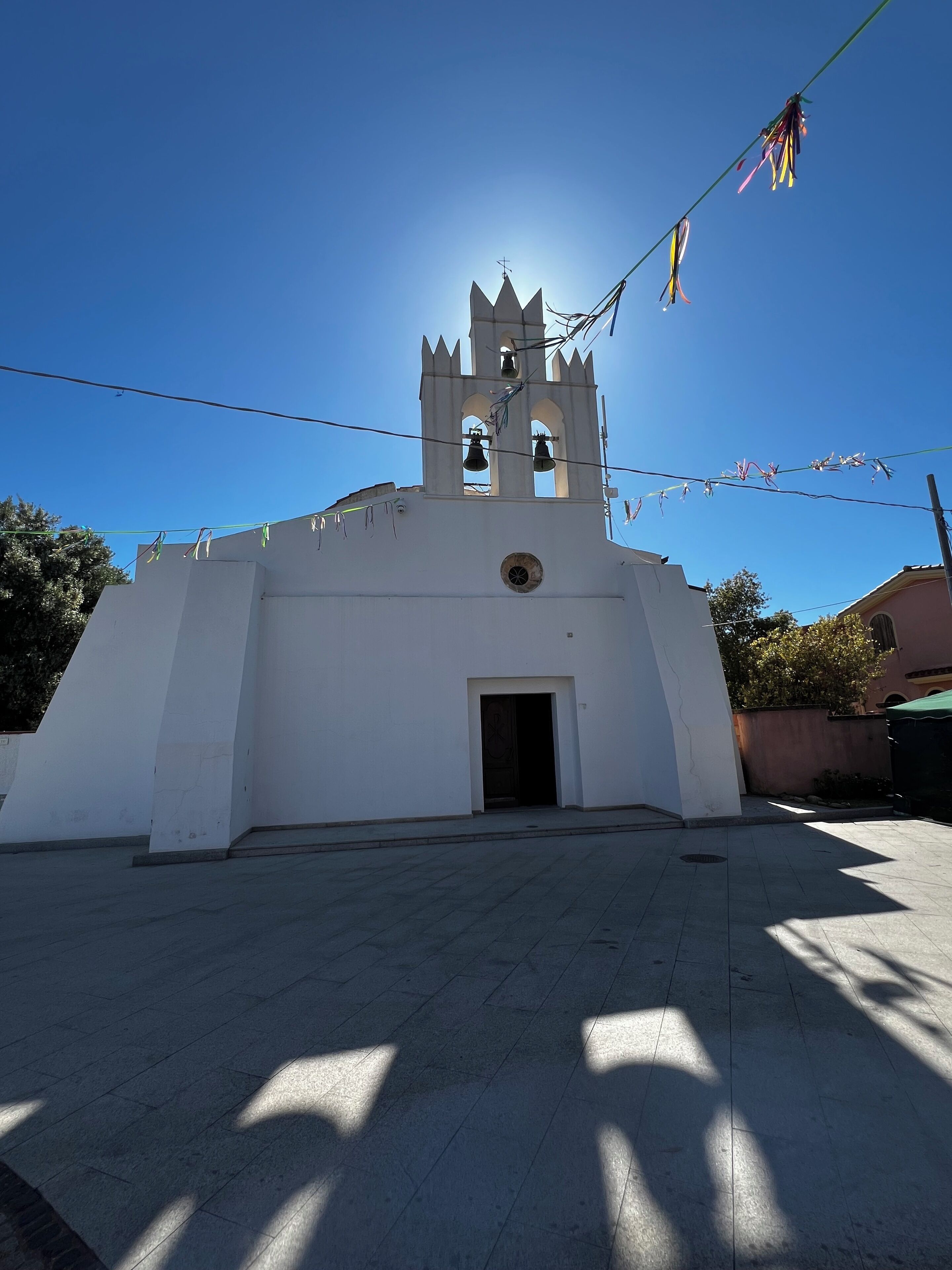 Una iglesia blanca con un campanario y una ventana circular.