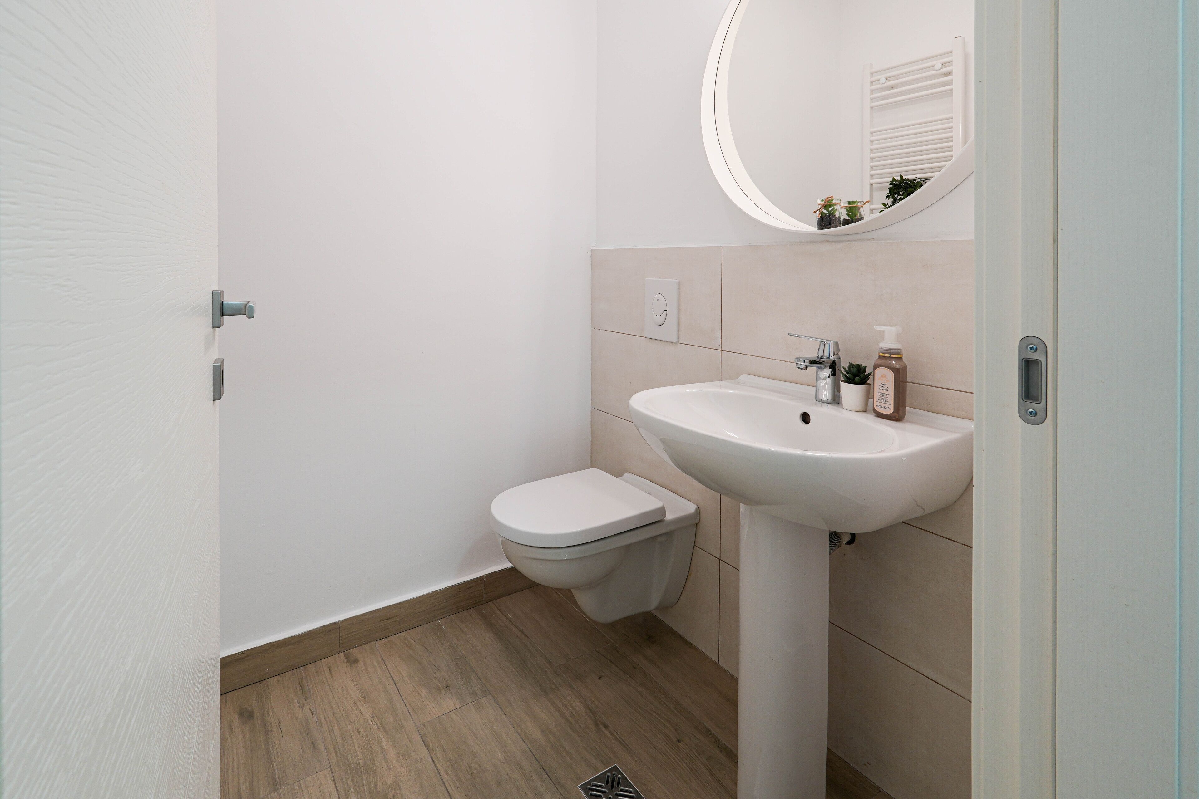 A bathroom with a toilet, sink, and mirror.