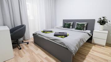 Un dormitorio moderno con cama, mesitas de noche, un escritorio y una silla.