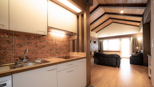A modern kitchen with white cabinets, a stainless steel sink, and a tiled backsplash. - Casa Viva (Bad Ragaz)
