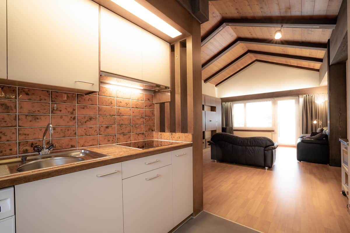 A modern kitchen with white cabinets, a stainless steel sink, and a tiled backsplash.