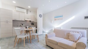 Une cuisine moderne avec des meubles blancs et un coin repas comprenant une table et des chaises blanches.