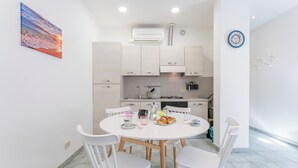 Une cuisine moderne avec des meubles blancs, une table de salle à manger ronde entourée de chaises blanches et un coin repas pour le petit-déjeuner.