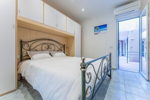 A bedroom with a bed, wooden headboard, white bedding, and a view through a glass door to the outside. - Casa Verdi near The Beach in Viareggio (Viareggio)