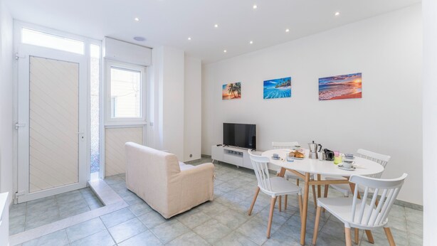 Un salon moderne avec un canapé, une table à manger, des chaises et des œuvres d’art accrochées au mur.