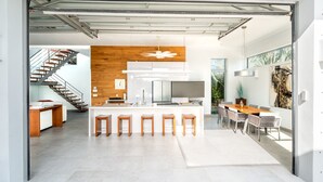 A modern kitchen with a central island, bar stools, and a dining area with a large table and chairs. - Vacation Villa Oceanview Hotel Amenities (Providenciales)