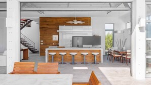 A modern kitchen with a central island, bar stools, and a dining area with a table and chairs. - Vacation Villa Oceanview Hotel Amenities (Providenciales)