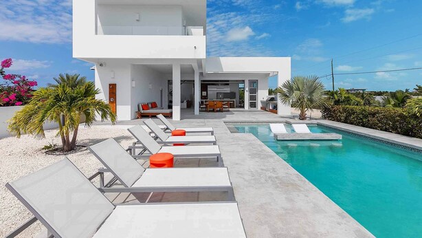 A modern two-story house with a swimming pool, outdoor seating, and a patio area. - Vacation Villa Oceanview Hotel Amenities (Providenciales)